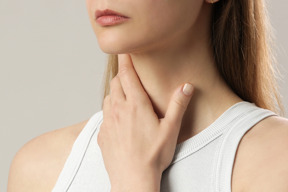 Woman touching her throat during an autoimmune condition assessment