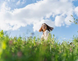 Woman walking through a sunlit meadow embracing personalized wellness