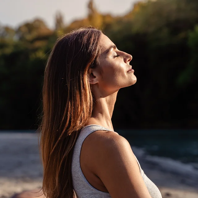Woman gazing across a green landscape at golden hour